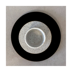 vista superior de xícara de café e pires com esmalte branco sobre prato de sobremesa preto em cerâmica artesanal